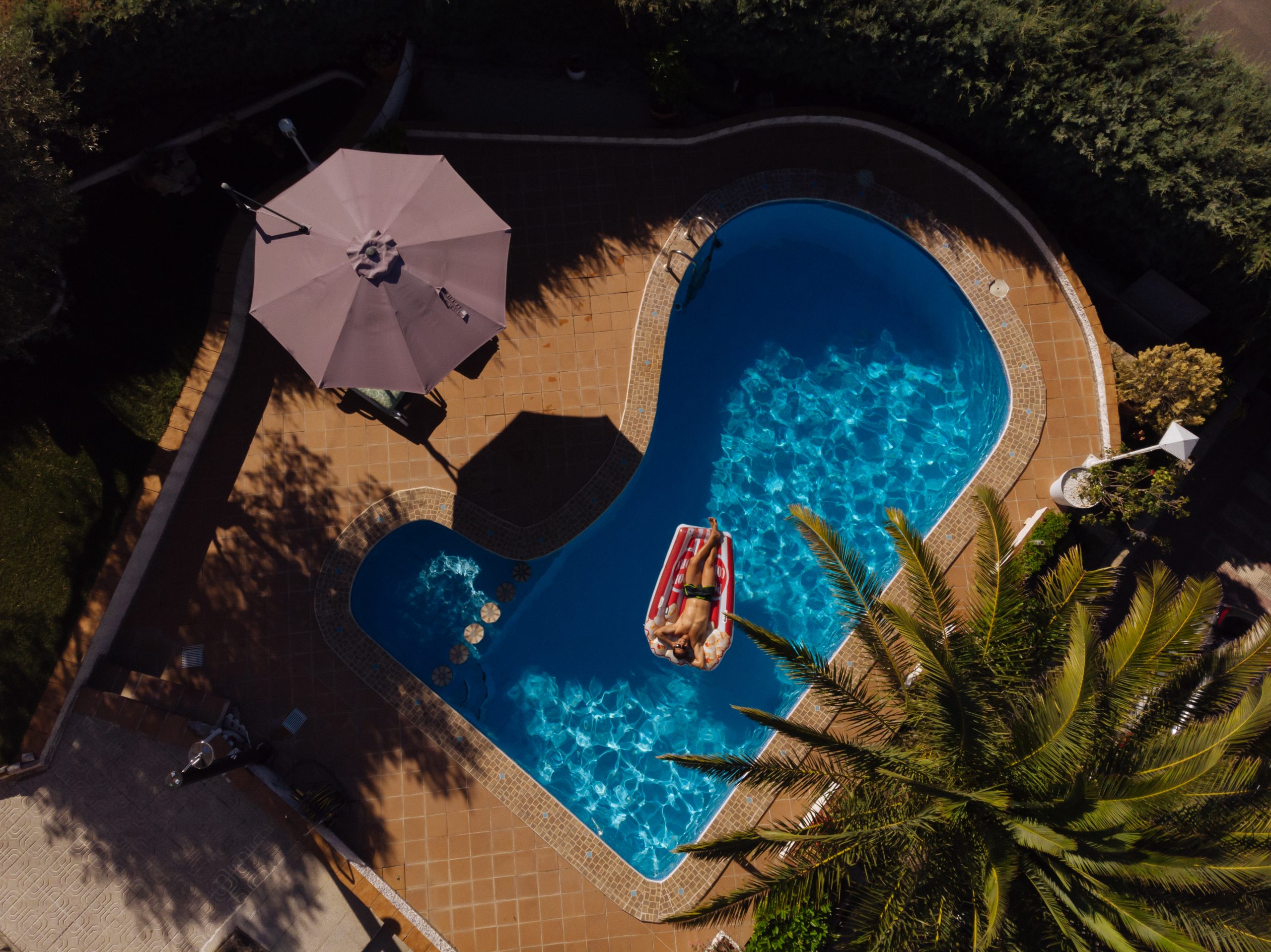 from above a man on beach mat in swimming pool of a villa house in a sunny day