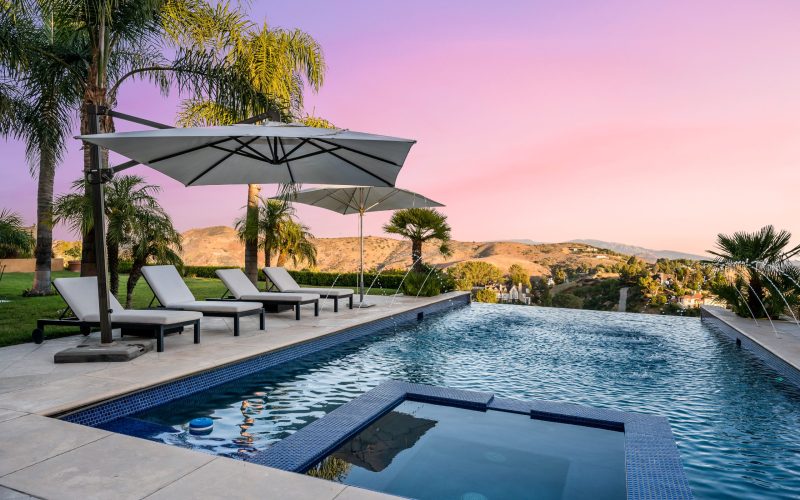Sunset view of a serene pool with loungers and umbrellas