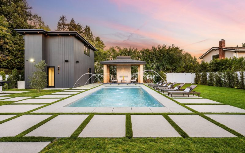 Modern backyard pool with sleek design, lounge chairs, and evening sky.